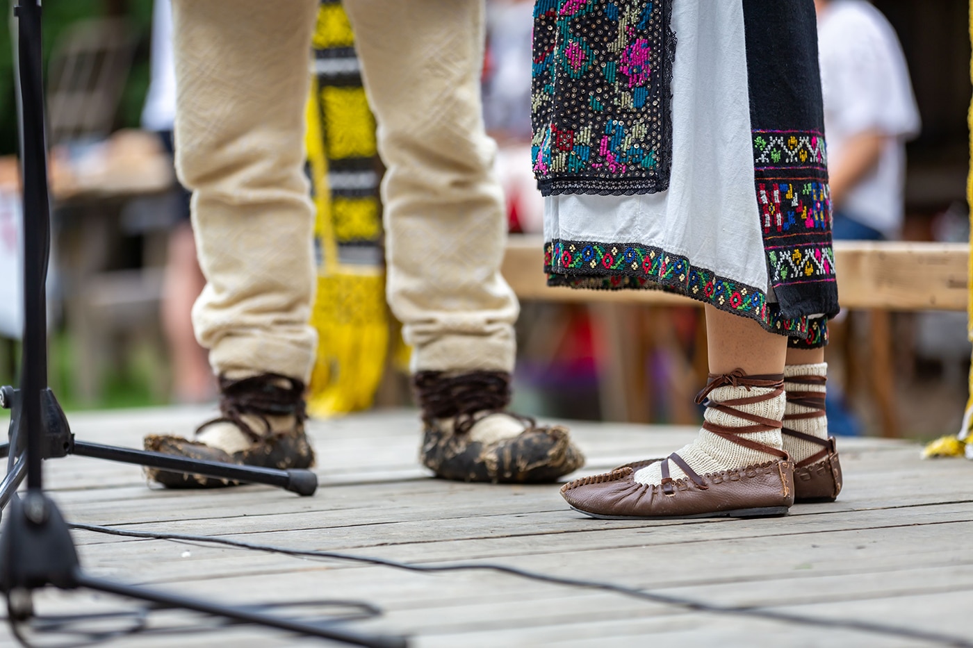 The view of a man's and woman's feet wearing leather sandals and an embroidered skirt